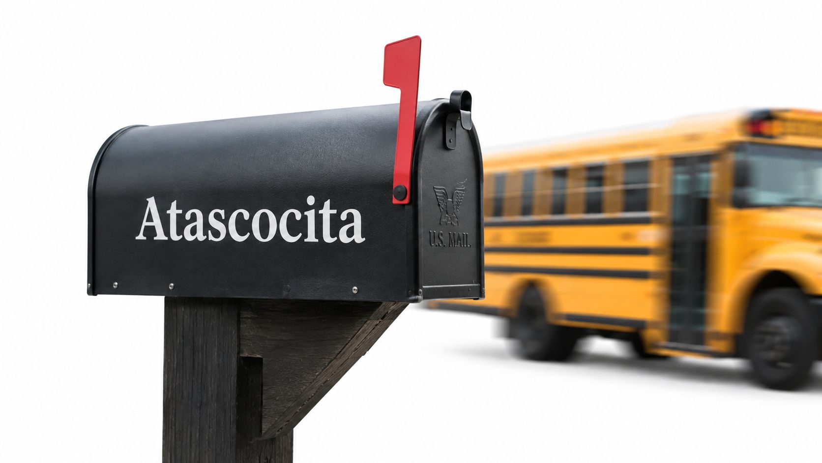 A black mailbox with the label Atascocita sits in front of a blurred yellow school bus.